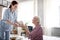 Red-haired nurse bringing breakfast for retired woman