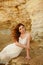 The red-haired sensual girl in white dress sitting on the rocks