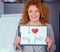 Red haired smiling businesswoman holding small poster.