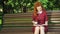 Red haired student studying in park and drinking coffee