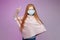 Red-haired teenage girl in a mask holds her index finger up. the concept of prevention covid19
