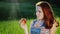 Red-haired teenager eating a juicy red apple on a picnic. A picturesque place - a green meadow, beautiful glare from the