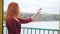 Red-haired thoughtful girl touches the glass with her hands