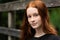 Red haired twelve year old girl with freckles posing with a nature bokeh background