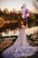 Red-haired woman with balloons in her hand and in a fairy purple dress at sunset