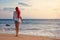 Red-haired woman enjoying the soothing sound of waves. Rear view of a beautiful woman finding peace by the ocean in a