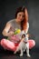 Red-haired woman holding a yellow tulip and playing with her puppy on a black background