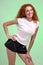 Red-haired woman in little shorts, isolated on green