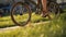 Red haired woman sitting on bicycle lying on grass in city park. Woman bike park