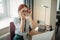 Red-haired woman sitting at table and working on laptop.