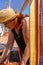 Red-haired woman in a straw hat tending her urban garden protected by net on the terrace of the house