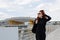 Red-haired woman in sunglasses and a black leather jacket against the background of an urban industrial landscape