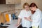 Red-haired woman teaches an elderly mother how to use a smartphone. Mother and adult daughter dressed in white blouses are