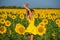 Red-haired woman in a yellow dress dancing with raised hands in a field of sunflowers. Beautiful girl in a skirt sun enjoys a