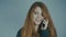 Red-haired young woman talking on the phone and smiling on studio background, concept emotions, communication, technology