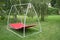 Red hammock swing in metal frame with nobody on green lawn in backyard. Rest relax relaxation alone on hammock swing in Summer