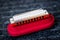 Red harmonica music instrument on top of its case