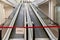 Red hazard safety tape across empty shopping mall escalator. Quarantine Zone, Do Not Cross.