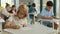 Red-head pupil wearing glasses sits at a first desk in the classroom and fills out tests thinking and writing down