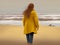 Red head woman walking on the beach looking at the rough sea in a cloudy day