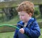 Red headed boy playing with water and toys in garden