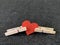 Red heart clamped clothespin, on a dark background. Sign of the heart in slavery. Concept: heart disease, addiction