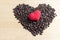 Red heart on coffee bean on wooden table