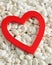 A red heart displayed on white pebbles