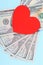 Red heart and Dollars banknotes on blue background. Business and love concept