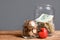 Red heart and donation jars with money on wooden table against grey background.