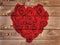 Red heart formed with roses on  rustic wooden  background