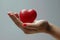 A red heart gently cradled in a hand with matching red nail polish. Generative AI