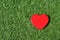 Red heart on green grass texture. Love natural.