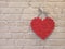 Red heart hanging on brick wall. Textured symbol of love. Lovers symbol