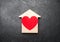 Red Heart inside a wooden house on a gray concrete background. The concept of a love nest, the search for new affordable housing
