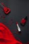 Red heart and lipstick, on a black background, a string of white pearls and a silk handkerchief