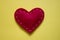 Red heart made of fabric with white threads on yellow background. Love, romance concept. Felt bright hearts with embroidered lines