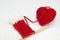 Red heart made of wool yarn. Red yarn ball like a heart and the beginning of red Santa scarf on the white crochet background. Roma