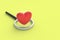 Red heart near magnifier on yellow background