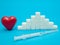 Red heart, pile of white sugar cubes, syringe with insulin