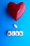 Red heart and pill on a blue background. Wooden cubes with the inscription RISK. The concept of health and timely medication