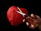 Red heart with scissors, on a black background. Paper heart with a slot inside. Crumpled paper in the shape of a heart. Concept: