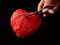 Red heart with scissors, on a black background. Paper heart with a slot inside. Crumpled paper in the shape of a heart. Concept: