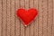 Red heart sewn from fabric on a knitted background. Valentine day card