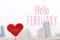 Red heart shape with Hello February text in city view background.