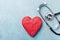 Red heart shape and medical stethoscope on blue background top view. Health care, medicare and cardiology concept.