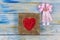 Red heart shape from thread bead on golden wooden frame with pin
