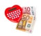 Red heart shaped calculator with euro banknotes.