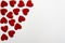 Red heart shaped confetti background or corner border over white. Top view, flat lay