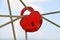 Red heart-shaped padlock hanging on the ropes on blue sky background